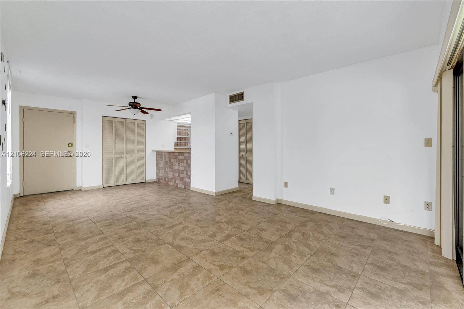 8887 Fontainebleau Boulevard, #206, Miami, Miami, FL 33172 Open interior space featuring tile flooring, a stone-accented breakfast bar, a ceiling fan with light fixture, and bi-fold closet doors