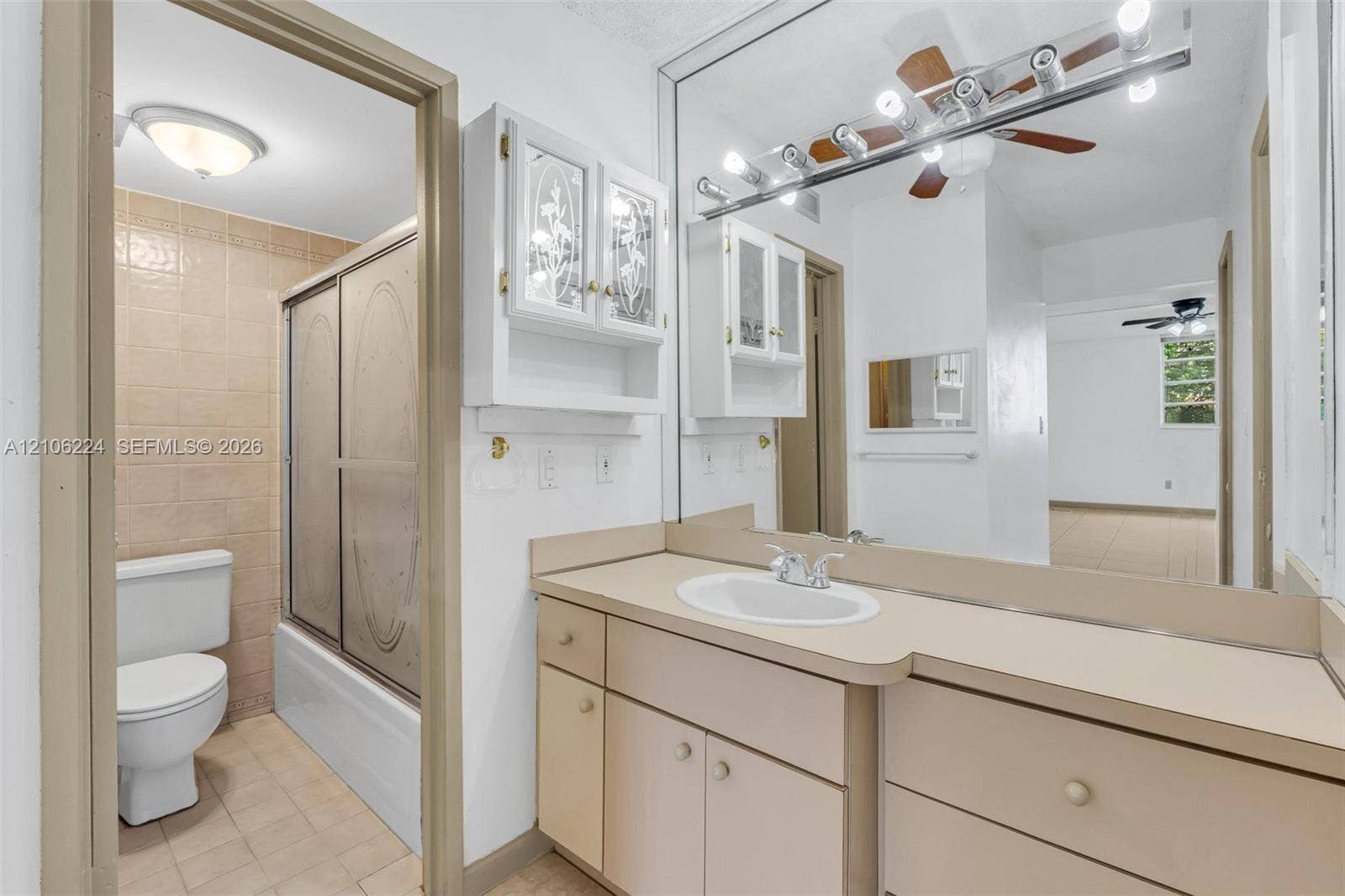 8887 Fontainebleau Boulevard, #206, Miami, Miami, FL 33172 Full-width vanity with integrated basin, expansive wall-to-wall mirror, cabinetry with glass-panel doors, and a tiled shower enclosure