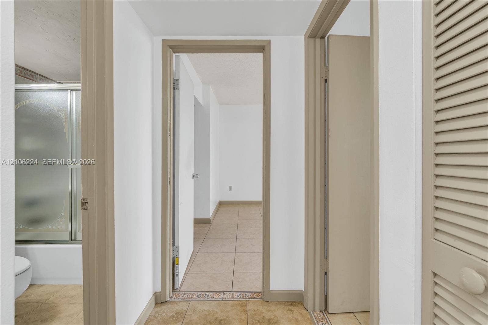 8887 Fontainebleau Boulevard, #206, Miami, Miami, FL 33172 Hallway featuring neutral-tone tile flooring, neutral wall finishes, and a louvered closet door