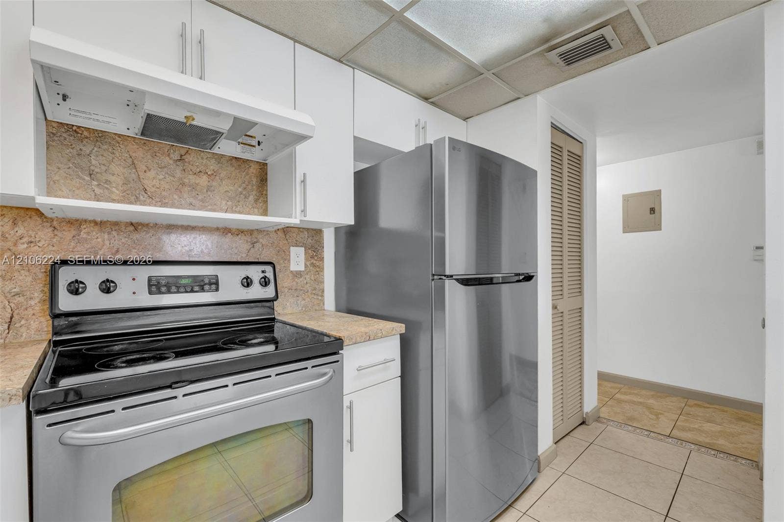 8887 Fontainebleau Boulevard, #206, Miami, Miami, FL 33172 Kitchen featuring white cabinetry, stainless steel appliances, stone-finish countertops, tiled backsplash, and ceramic floor tile