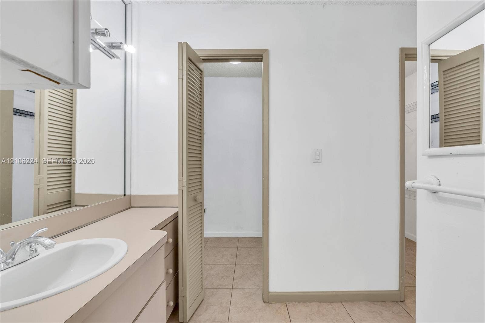 8887 Fontainebleau Boulevard, #206, Miami, Miami, FL 33172 Vanity featuring a neutral countertop with an integrated oval basin, full-width mirror, louvered closet doors, and tile flooring