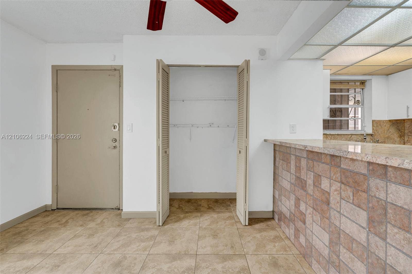 8887 Fontainebleau Boulevard, #206, Miami, Miami, FL 33172 Ceramic tile flooring, louvered bi-fold closet doors, a kitchen peninsula with a stone-finish countertop and tiled base, and recessed ceiling lighting