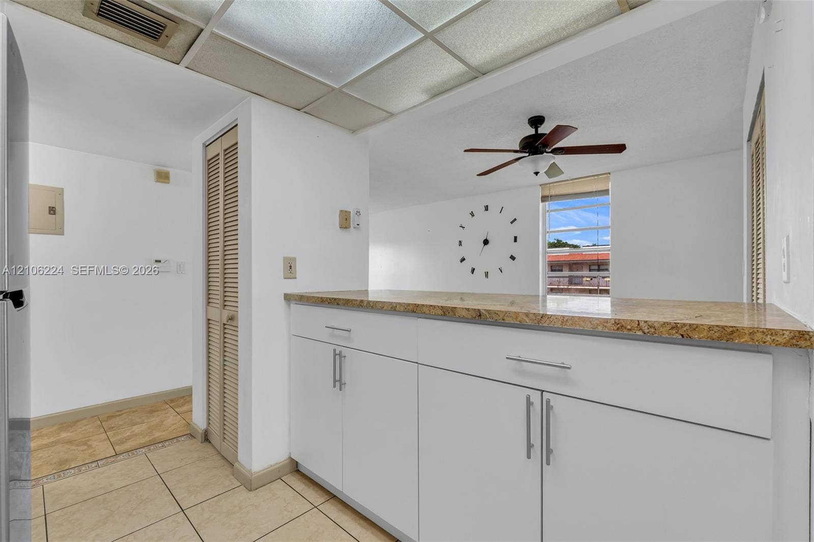 8887 Fontainebleau Boulevard, #206, Miami, Miami, FL 33172 Kitchen area featuring white cabinetry, stone-finish countertops, tile flooring, and a ceiling-mounted fan
