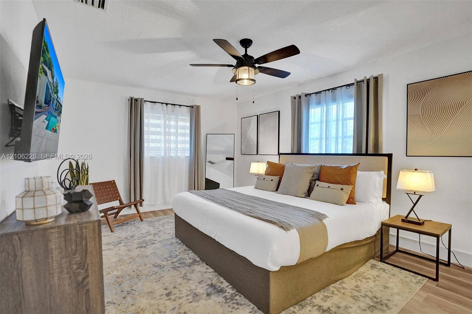 11155 SW 40th Street, Davie, FL 33328 Neutral-toned interior featuring wood-finish flooring, a multi-blade ceiling fan with integrated lighting, and dual windows with window treatments