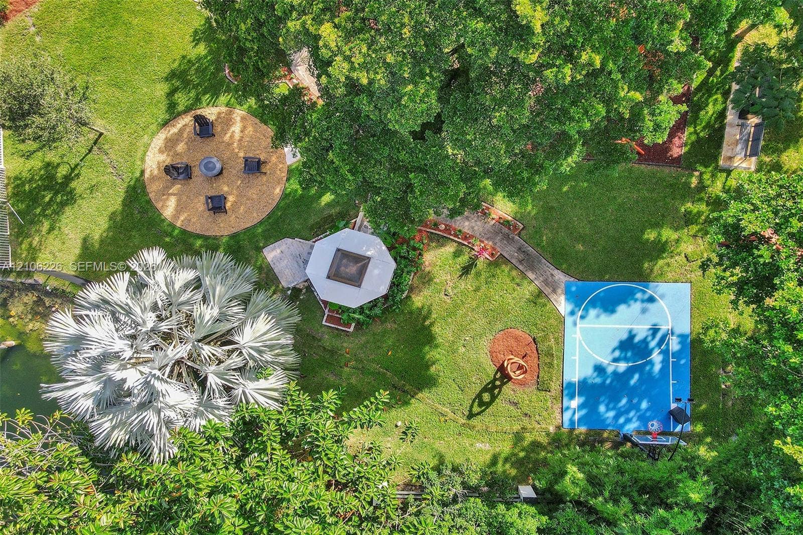 11155 SW 40th Street, Davie, FL 33328 Expansive grounds featuring a dedicated basketball court, a custom gazebo, a circular mulched gathering area, and mature landscaping