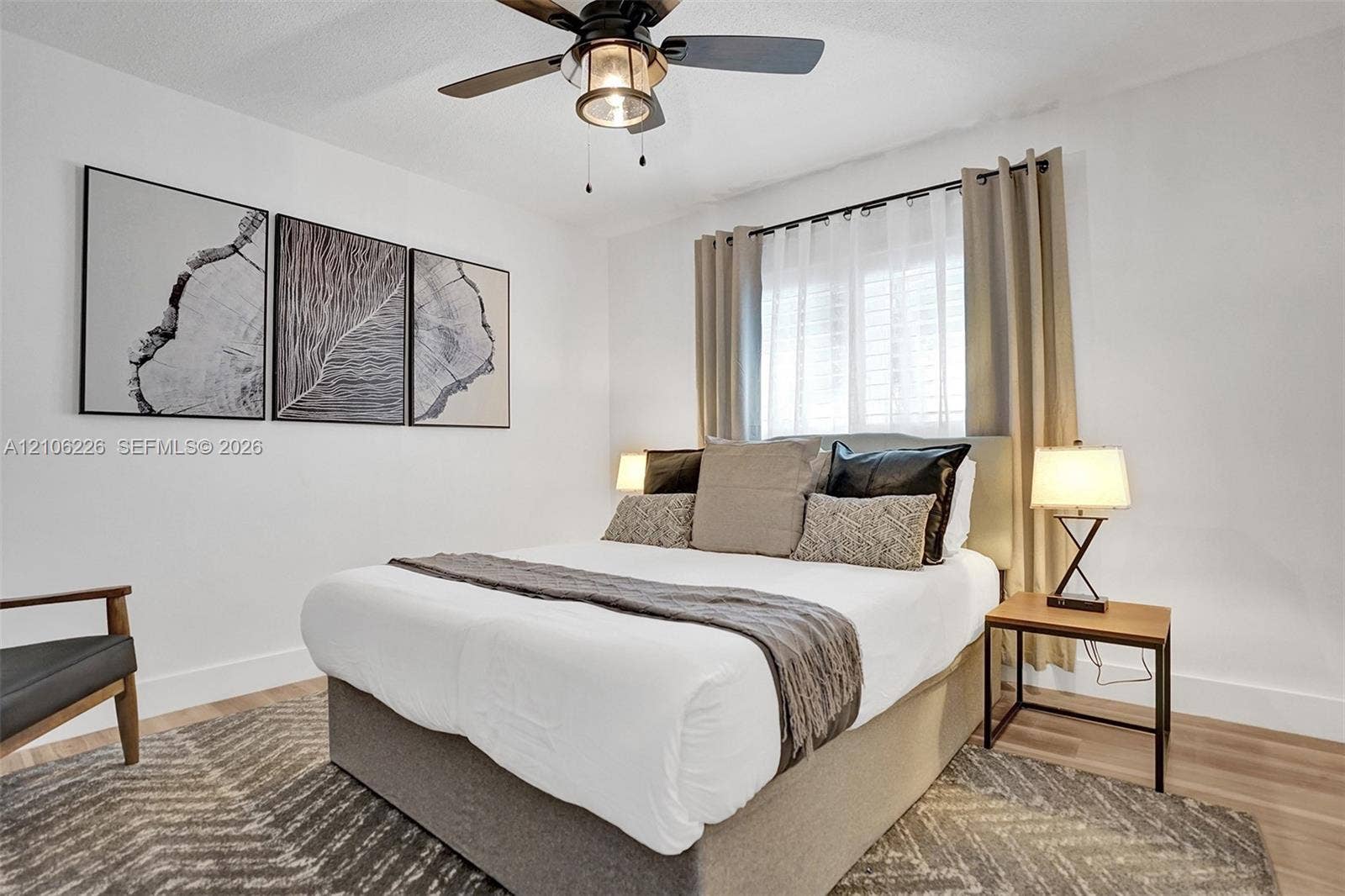 11155 SW 40th Street, Davie, FL 33328 Neutral-toned room featuring wood-finish flooring, a multi-blade ceiling fan with integrated lighting, and a window with plantation-style shutters