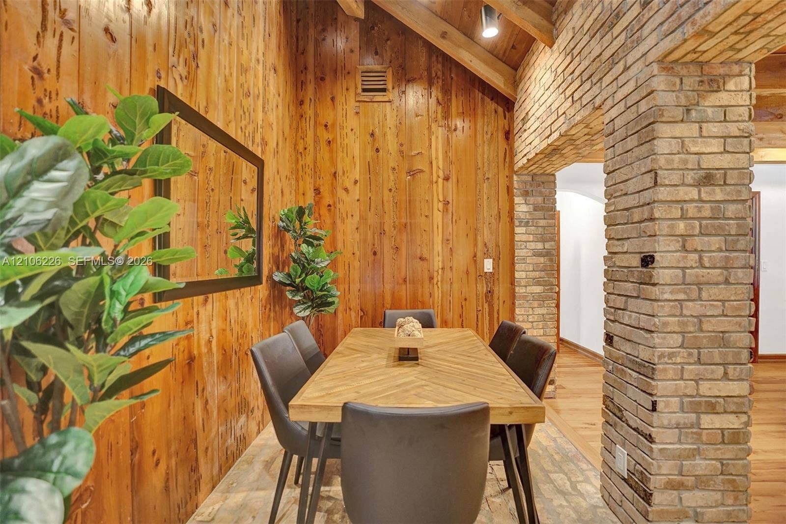11155 SW 40th Street, Davie, FL 33328 Vaulted ceiling featuring exposed wood beams, vertical wood-paneled walls, and a structural brick column