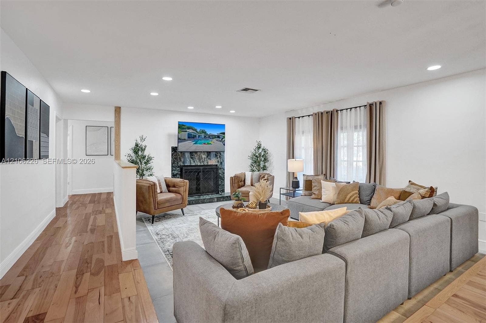 11155 SW 40th Street, Davie, FL 33328 Living area featuring wood-finish flooring, a full-height stone-surround fireplace, recessed ceiling lighting, and large windows with floor-to-ceiling drapery