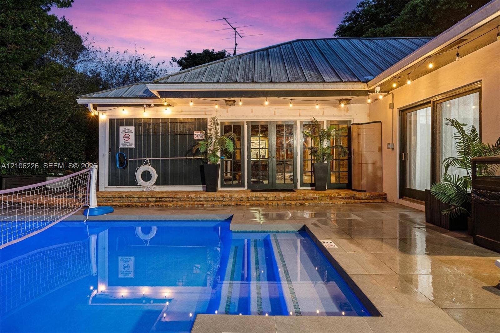 11155 SW 40th Street, Davie, FL 33328 In-ground swimming pool with integrated stair entry, metal roof, paved patio surround, and glass-paneled double doors