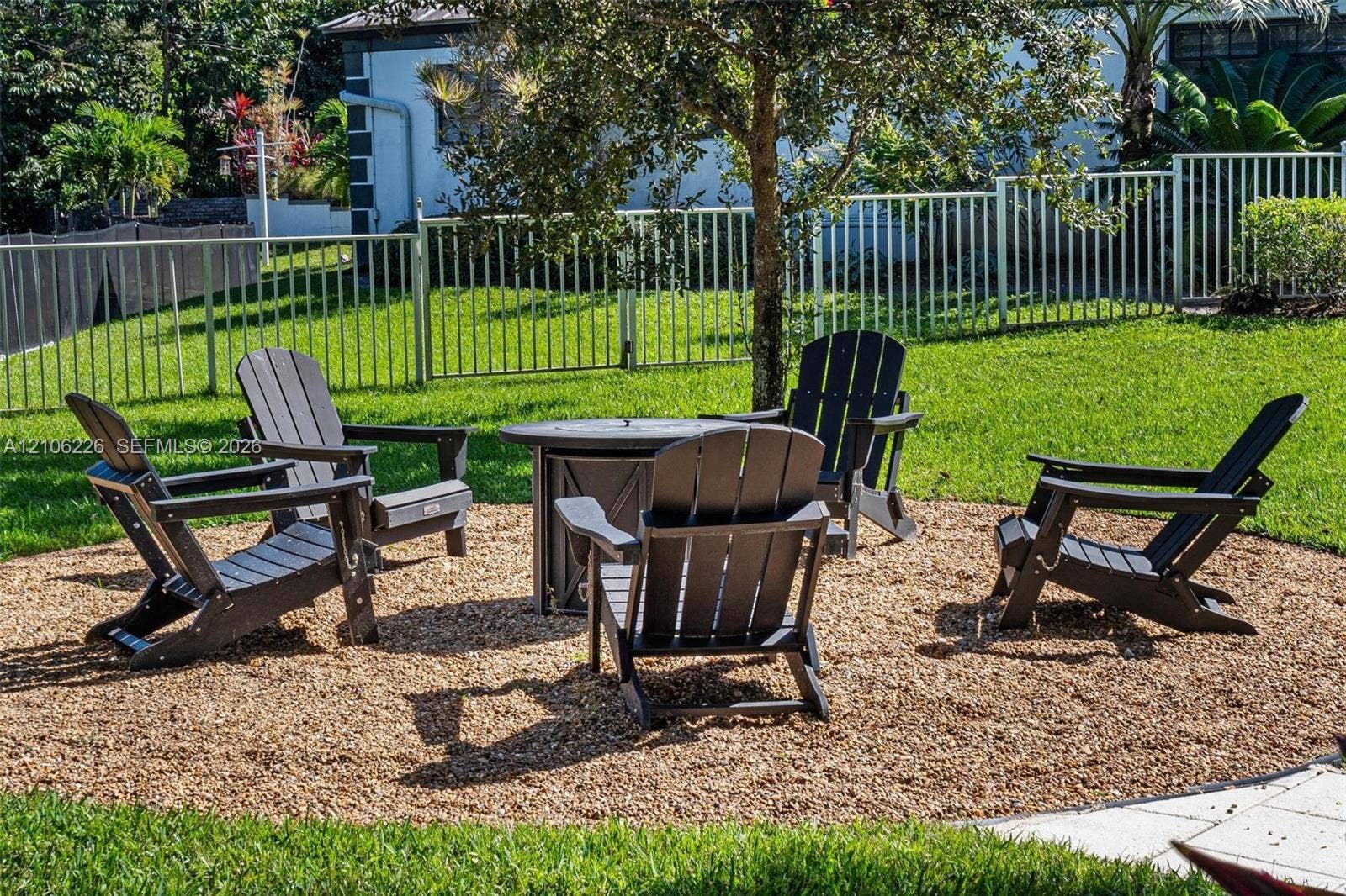11155 SW 40th Street, Davie, FL 33328 Fenced backyard featuring a gravel fire pit area, mature trees, and a manicured lawn