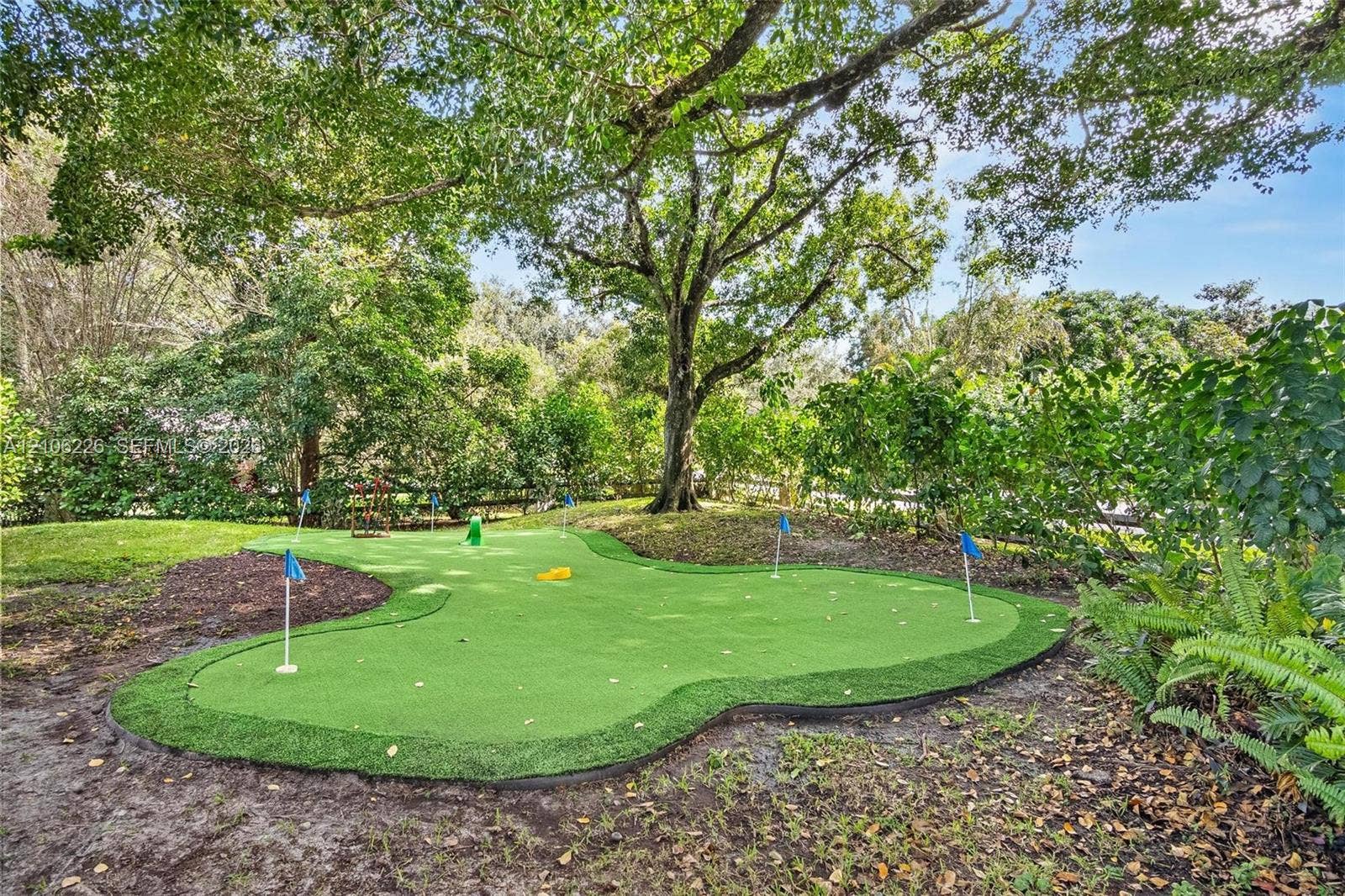 11155 SW 40th Street, Davie, FL 33328 Backyard putting green featuring synthetic turf, multiple flag pins, and mature canopy trees