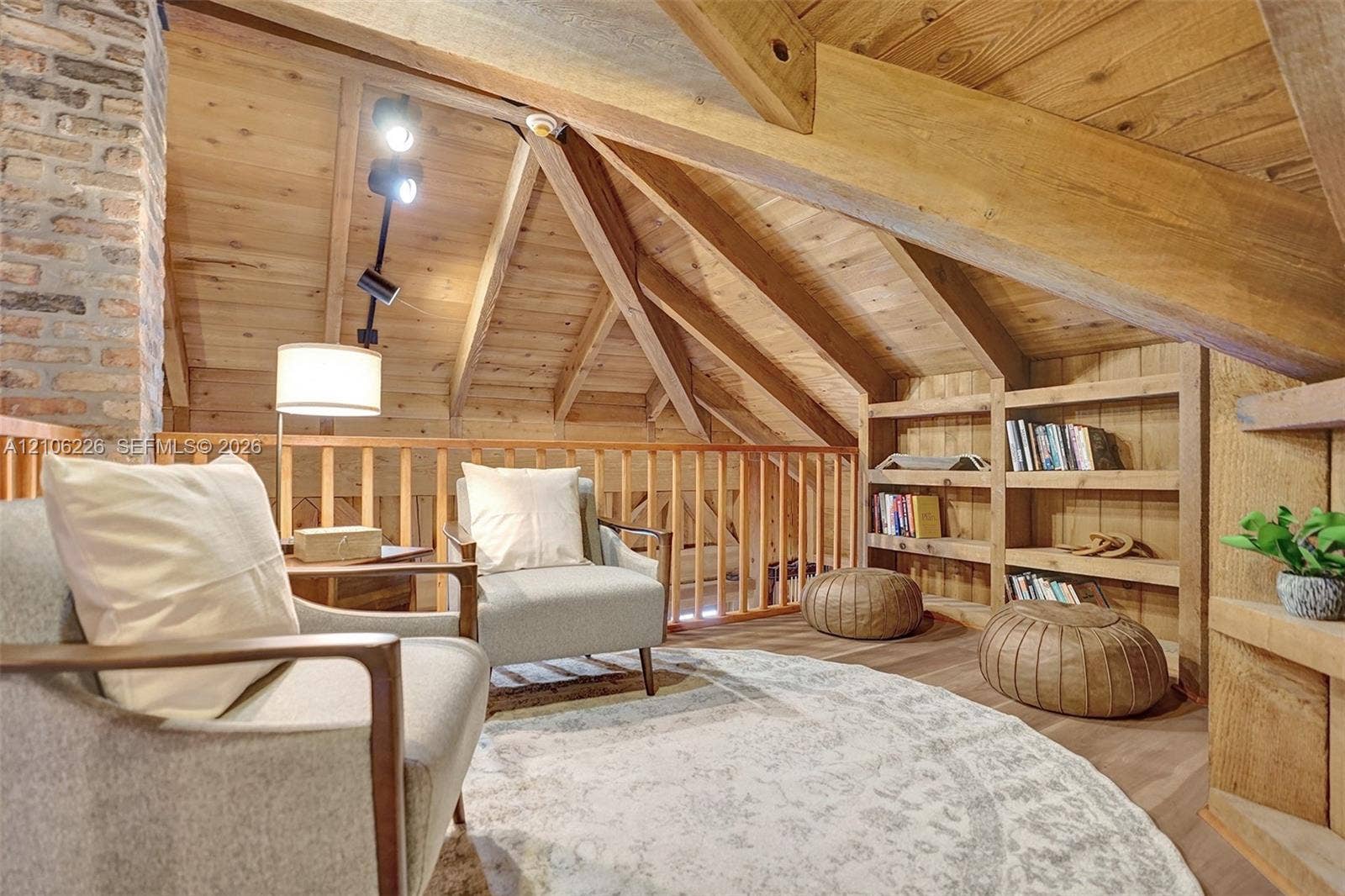 11155 SW 40th Street, Davie, FL 33328 Vaulted ceilings featuring exposed timber beams, wood-plank wall and ceiling paneling, a full-height brick chimney, custom built-in wooden shelving, and an integrated wooden railing