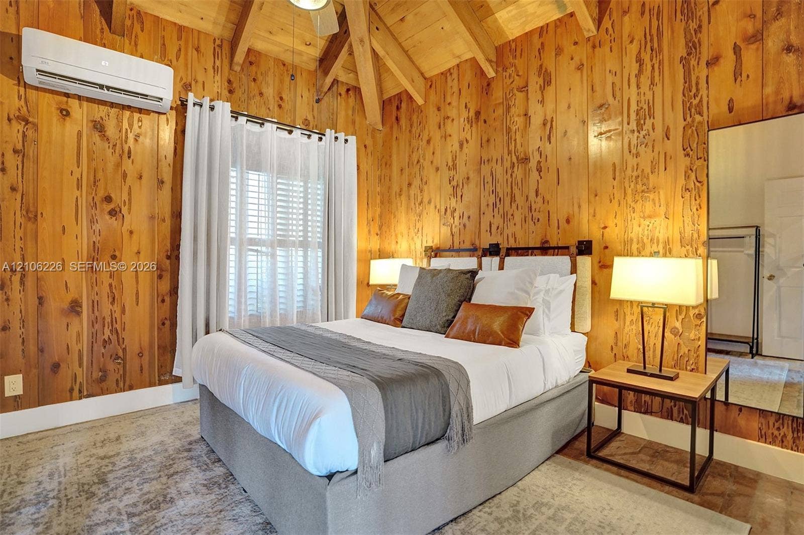 11155 SW 40th Street, Davie, FL 33328 Vaulted ceiling with exposed wood beams, full-height knotty wood-paneled walls, wall-mounted ductless climate control unit, and wood-finish flooring