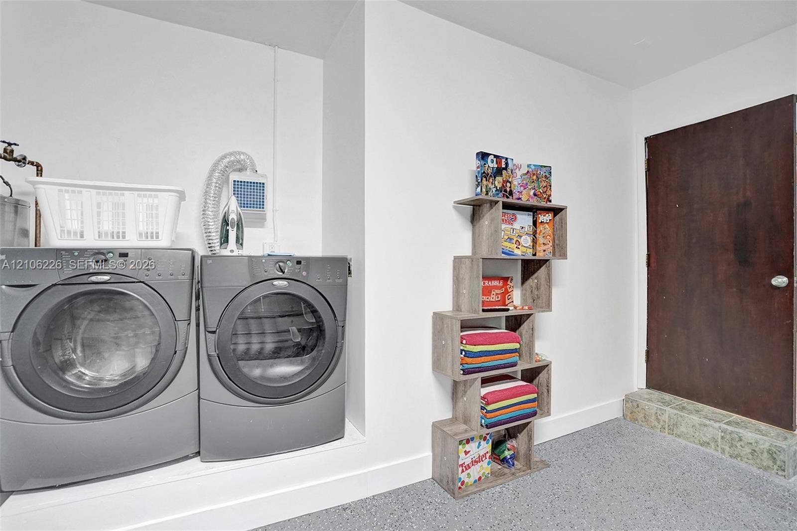 11155 SW 40th Street, Davie, FL 33328 Laundry area featuring side-by-side front-load appliances, dedicated water hookups, and a solid-core wood door with a tiled threshold
