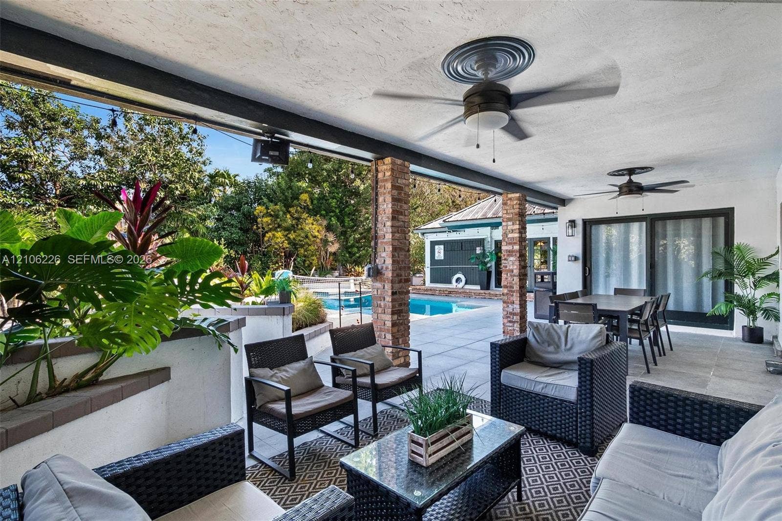 11155 SW 40th Street, Davie, FL 33328 Covered patio featuring exposed brick columns, concrete tile flooring, dual ceiling fans, and integrated lighting