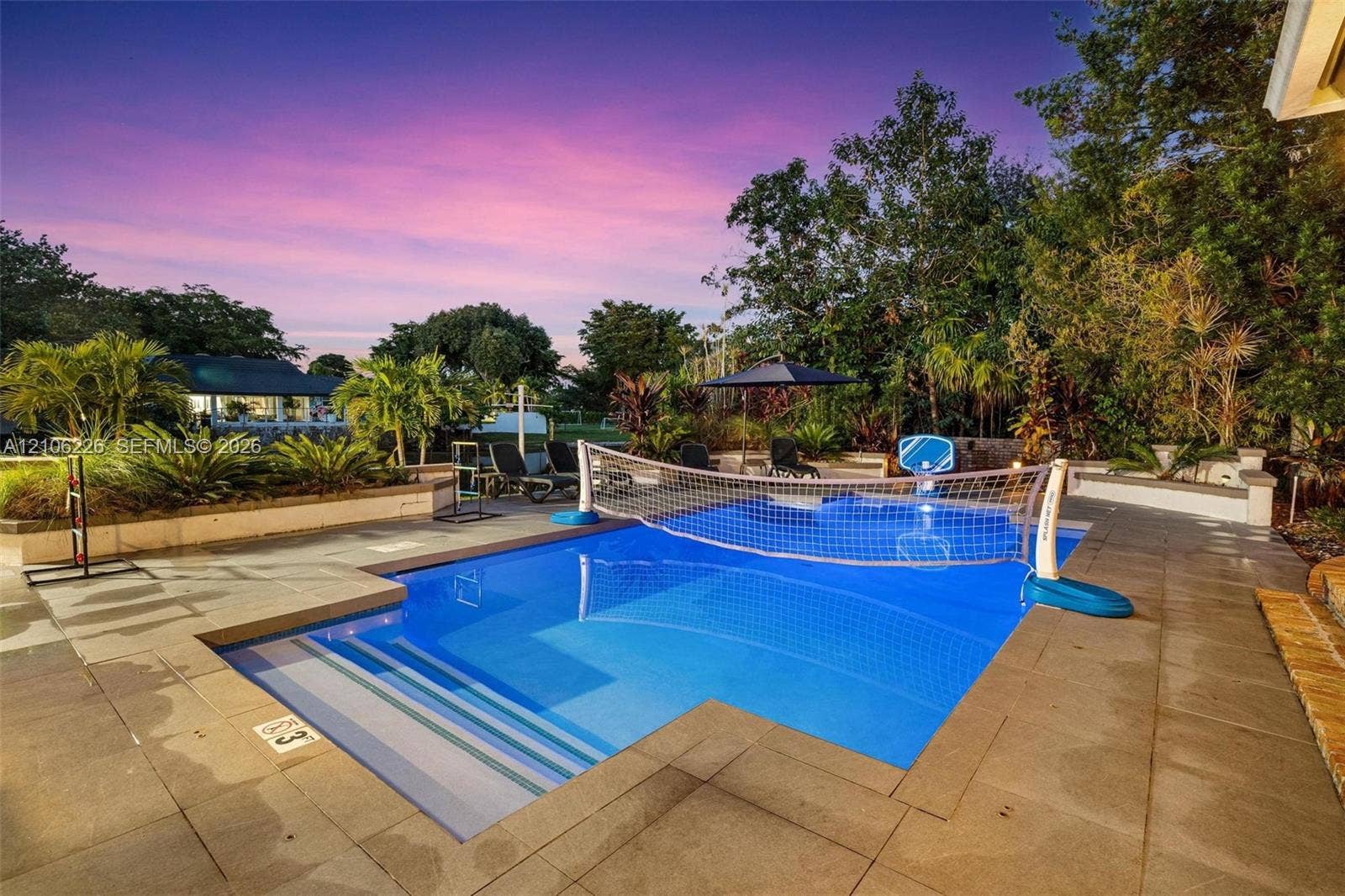 11155 SW 40th Street, Davie, FL 33328 Swimming pool with integrated entry steps and stone paver decking, surrounded by mature landscaping and hardscaped planter beds