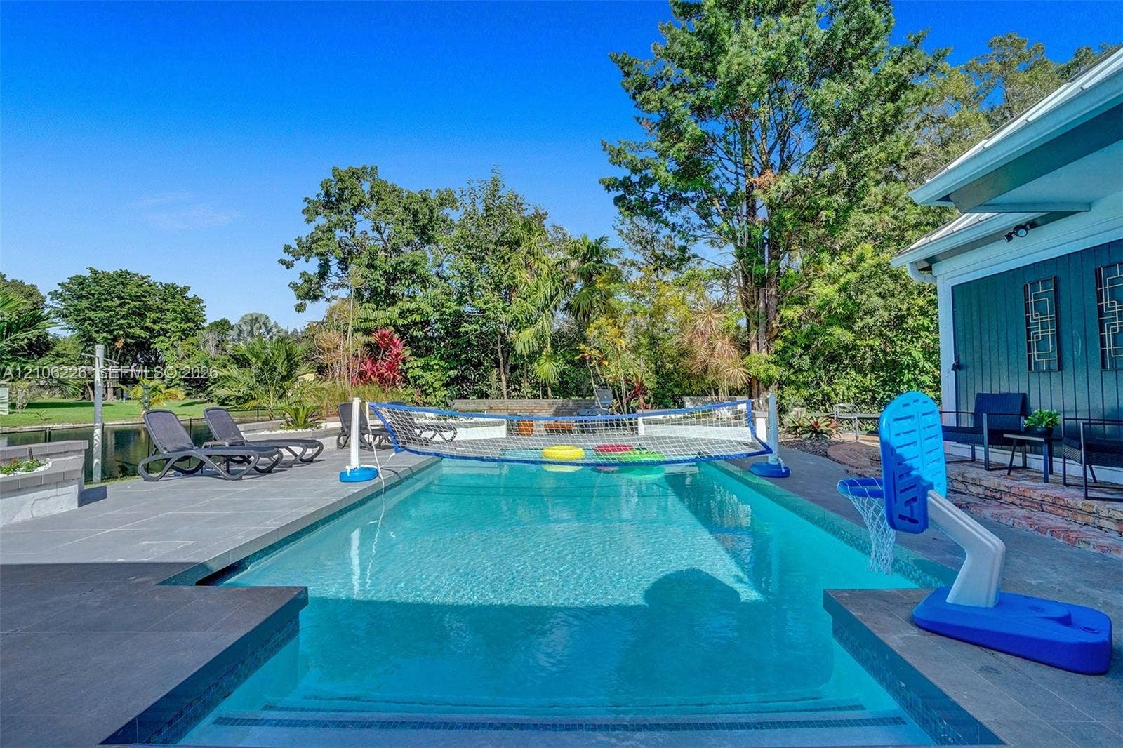 11155 SW 40th Street, Davie, FL 33328 In-ground swimming pool featuring a perimeter of large-format stone tile decking and stone block retaining walls