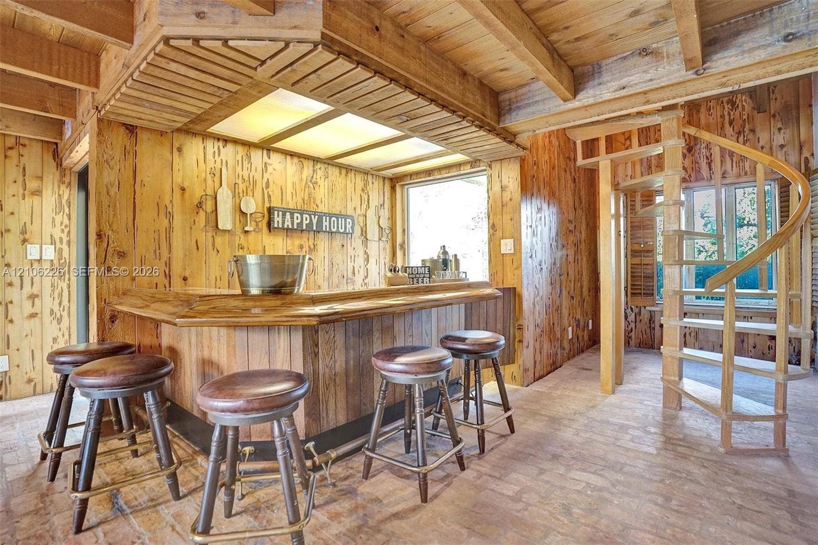 11155 SW 40th Street, Davie, FL 33328 Custom built-in wood bar featuring recessed lighting, paneled wood walls, wood beam ceiling, and a spiral staircase