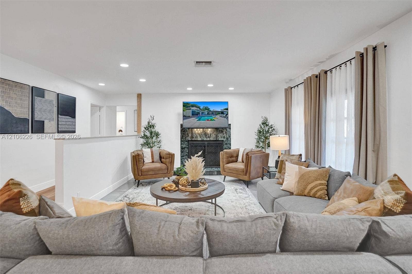 11155 SW 40th Street, Davie, FL 33328 Spacious living area featuring recessed lighting, a fireplace with dark stone surround, and floor-to-ceiling windows
