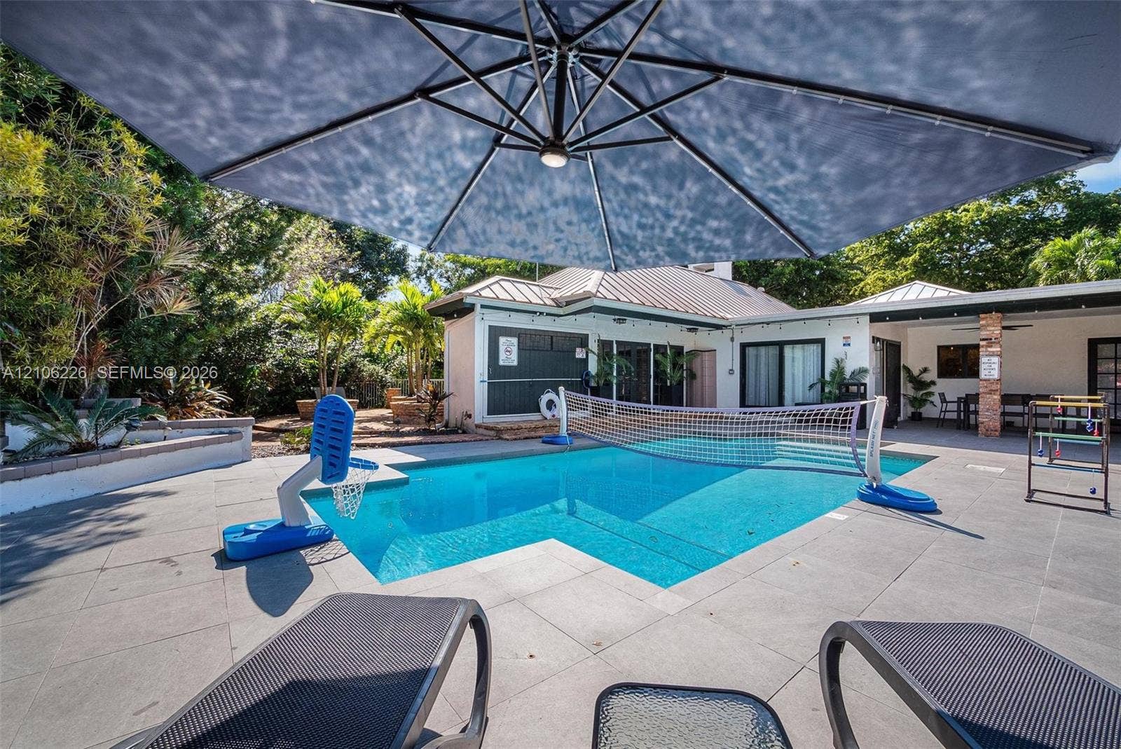 11155 SW 40th Street, Davie, FL 33328 Private backyard featuring a swimming pool, large concrete paver patio, covered porch area, and mature landscaping