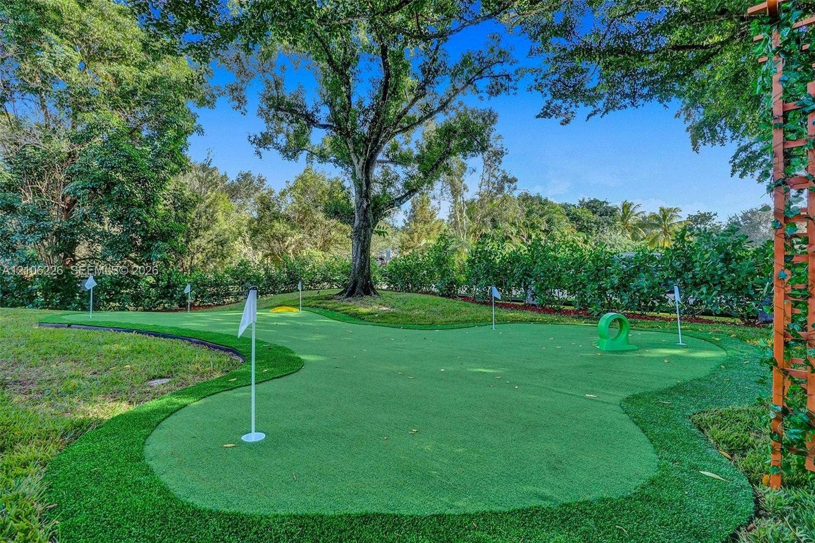 11155 SW 40th Street, Davie, FL 33328 Putting green featuring synthetic turf, multiple flag pins, and mature canopy trees