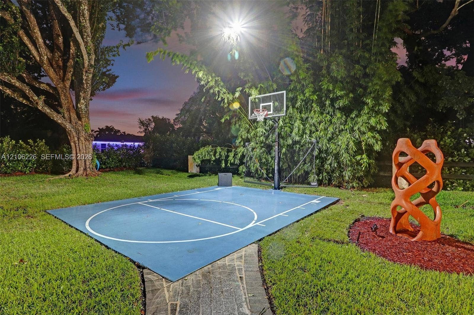 11155 SW 40th Street, Davie, FL 33328 Backyard featuring a dedicated half-court basketball pad, stone pathway, and mature landscaping