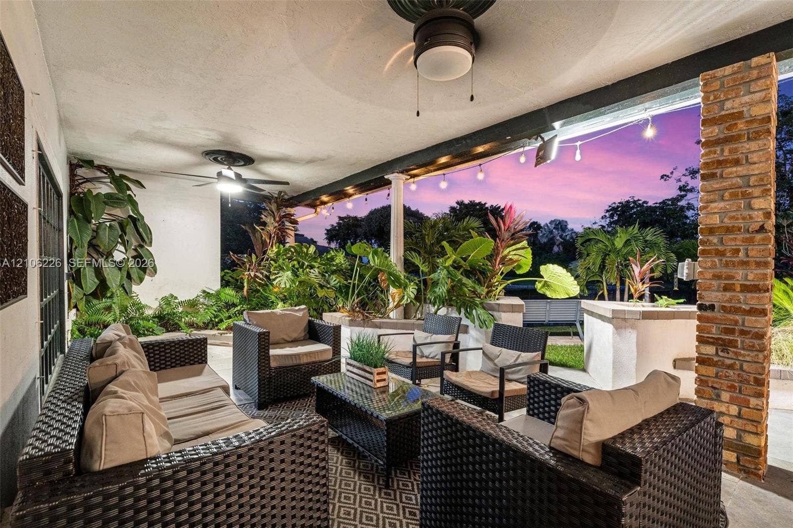 11155 SW 40th Street, Davie, FL 33328 Covered patio featuring a brick support column, dual ceiling fans, and string lighting