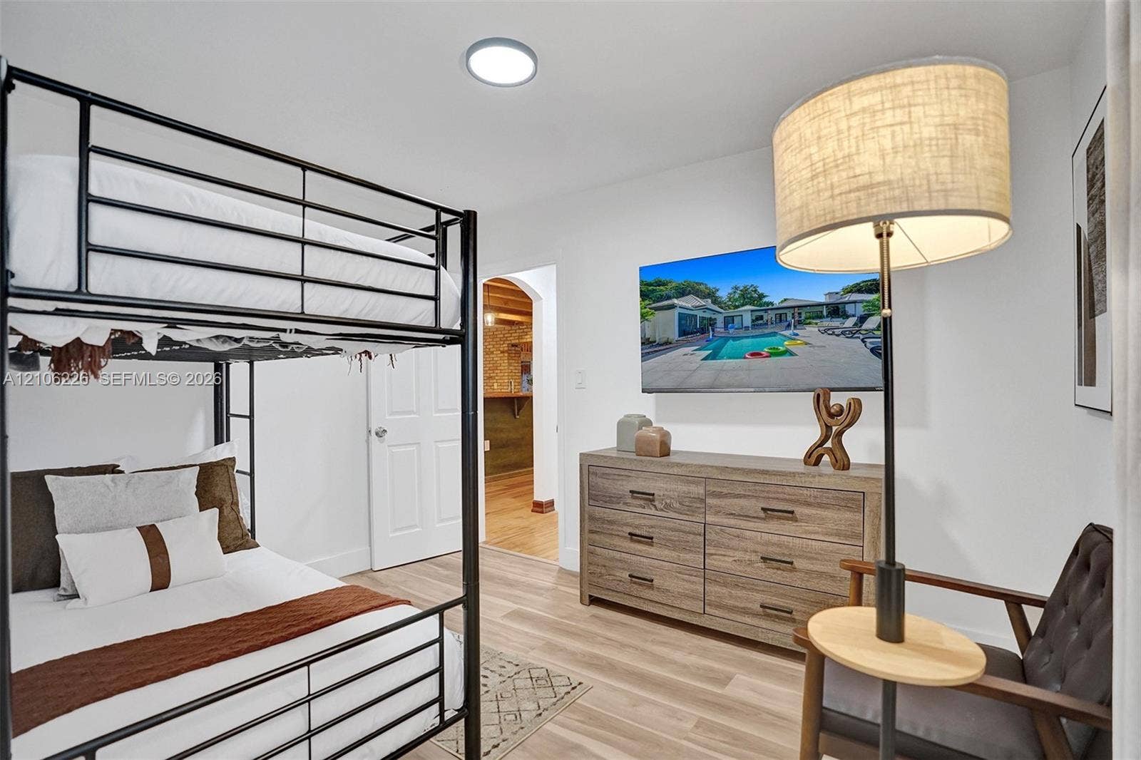 11155 SW 40th Street, Davie, FL 33328 Neutral-toned room featuring wood-finish flooring, a flush-mount circular ceiling light, a white paneled door, and an arched entryway