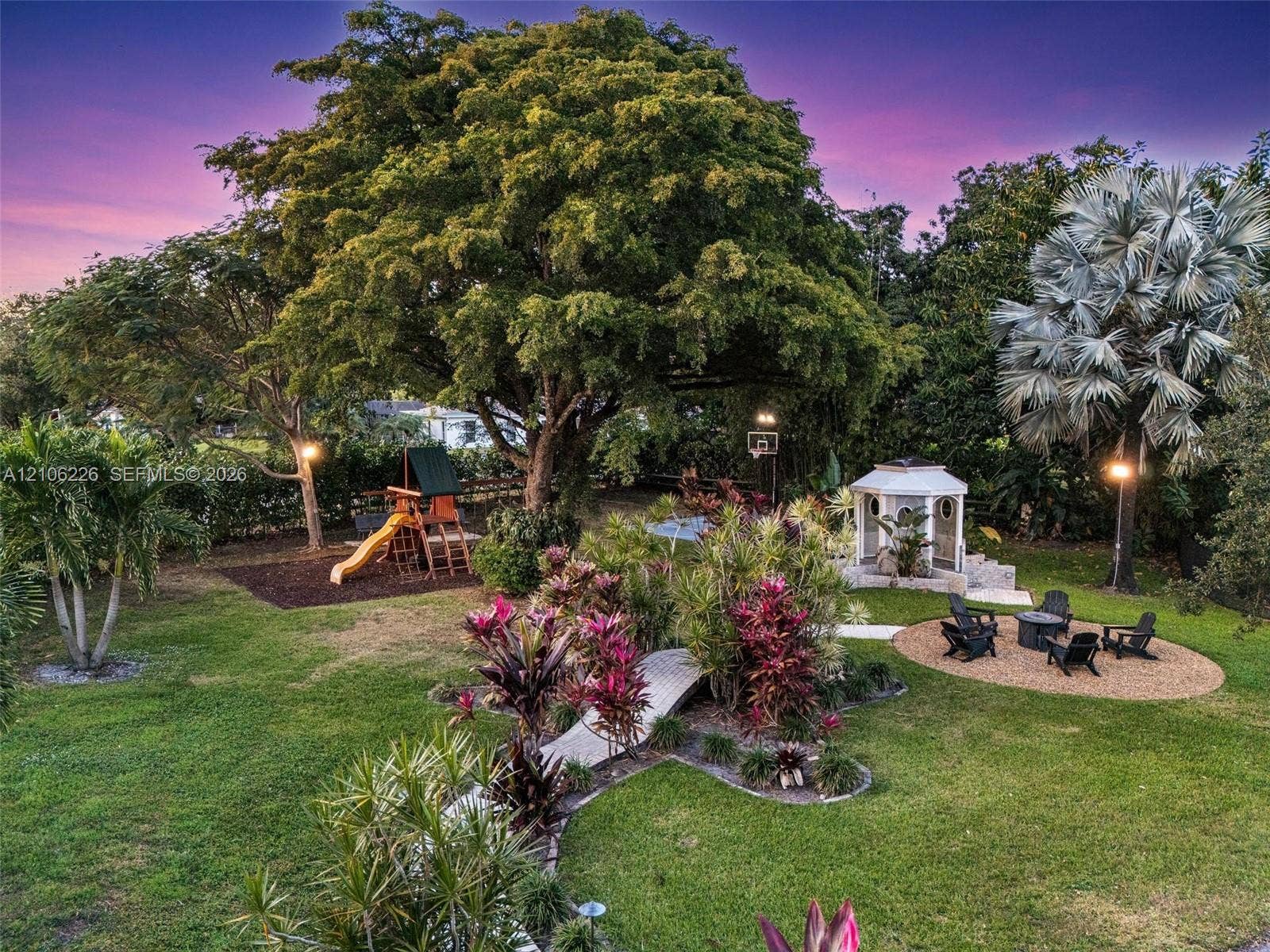 11155 SW 40th Street, Davie, FL 33328 Expansive backyard featuring mature shade trees, a stone-paved walkway, a structural gazebo, and an integrated play area with wood-mulch surfacing