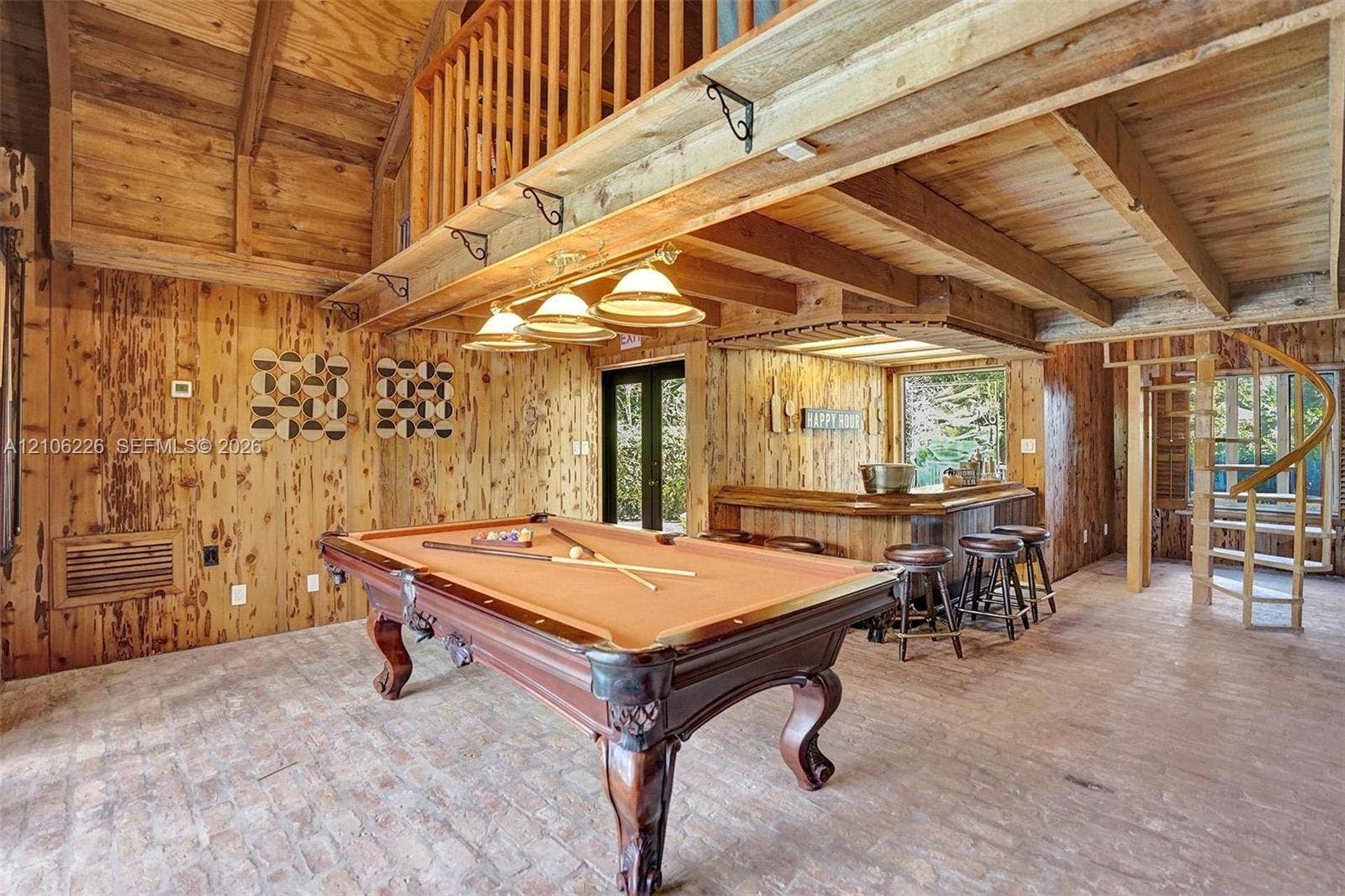 11155 SW 40th Street, Davie, FL 33328 Vaulted ceiling with exposed wood beams, wood-paneled walls, brick flooring, built-in bar, and spiral staircase
