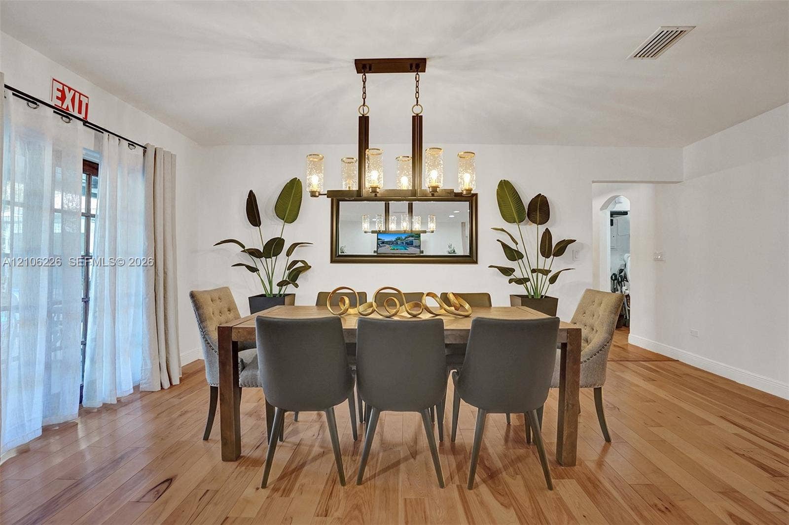 11155 SW 40th Street, Davie, FL 33328 Dining area featuring wood-finish flooring, a linear multi-light metal chandelier, and a wall-mounted framed mirror