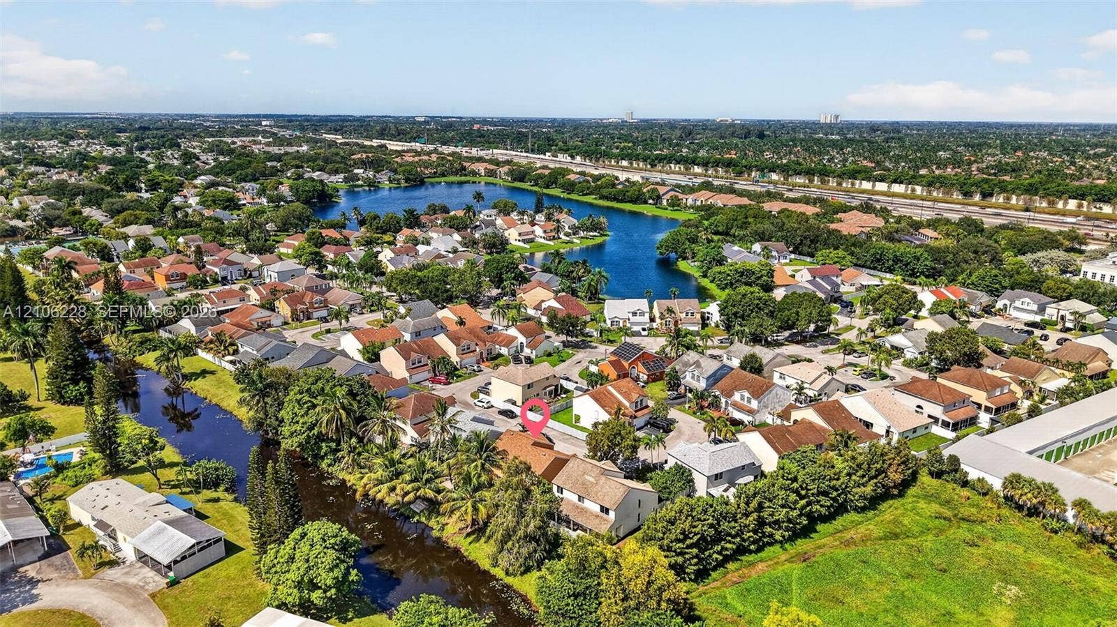 10760 SW 11th Drive, Davie, FL 33324 Aerial perspective of a multi-level suburban residence featuring a concrete tile roof, paved driveway, and placement along a waterfront canal