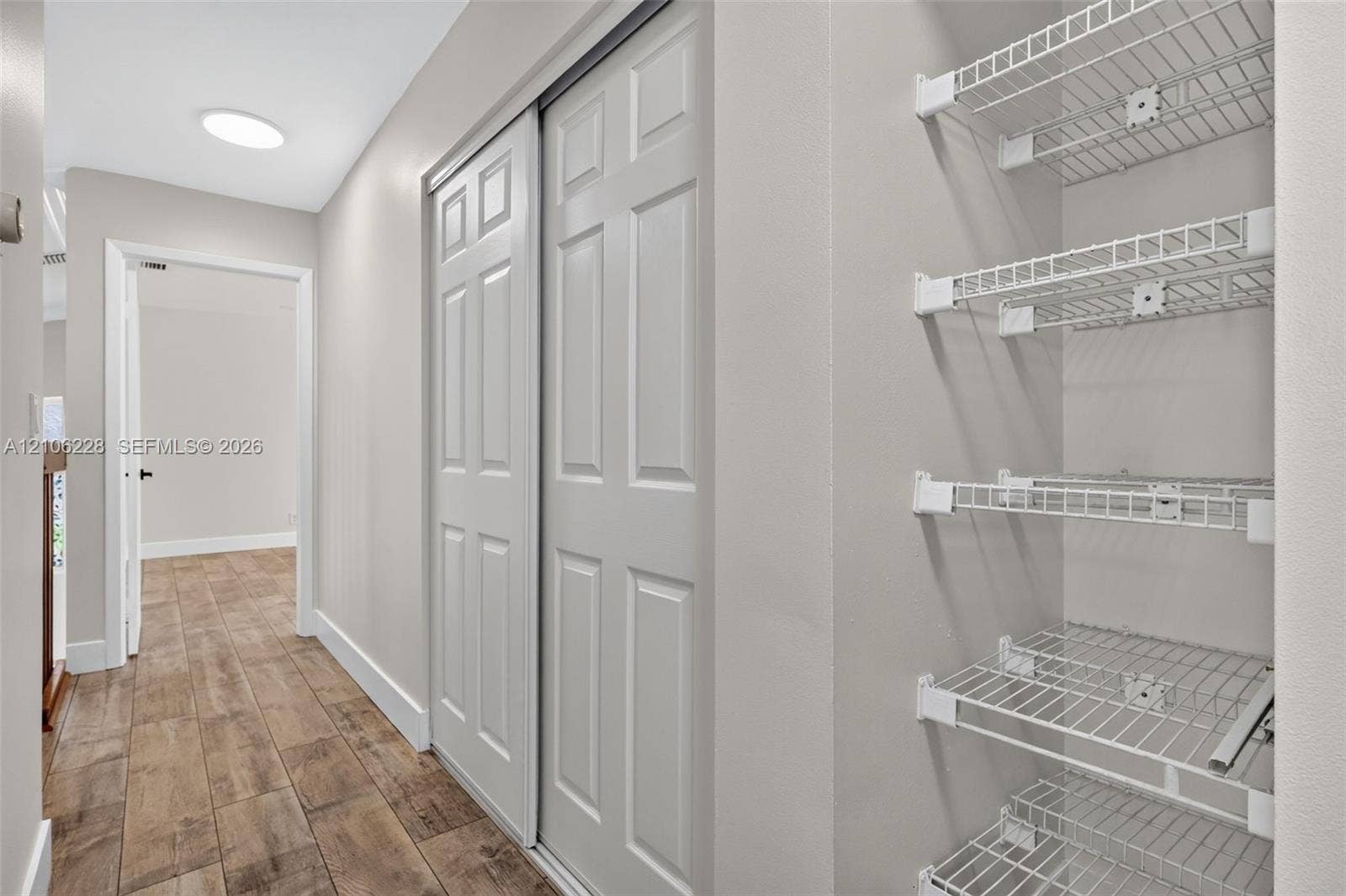 10760 SW 11th Drive, Davie, FL 33324 Storage area featuring white wire shelving, paneled sliding closet doors, and wood-finish flooring