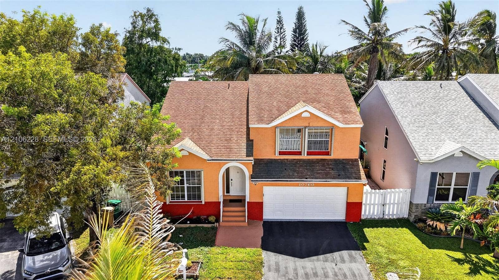 10760 SW 11th Drive, Davie, FL 33324 Two-story exterior featuring a shingled roof, arched entryway, multi-tone facade, attached two-car garage, and a paved driveway
