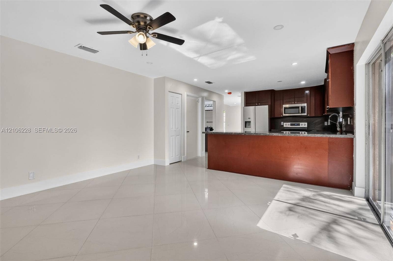 10760 SW 11th Drive, Davie, FL 33324 Kitchen featuring dark-toned wood cabinetry, stone countertops, stainless steel appliances, breakfast bar, and polished tile flooring