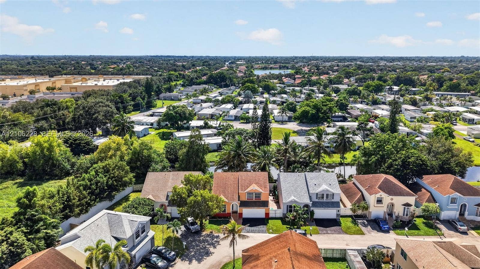10760 SW 11th Drive, Davie, FL 33324 Aerial perspective of a suburban neighborhood featuring multi-story residences, shingle roofing, mature trees, and canal frontage