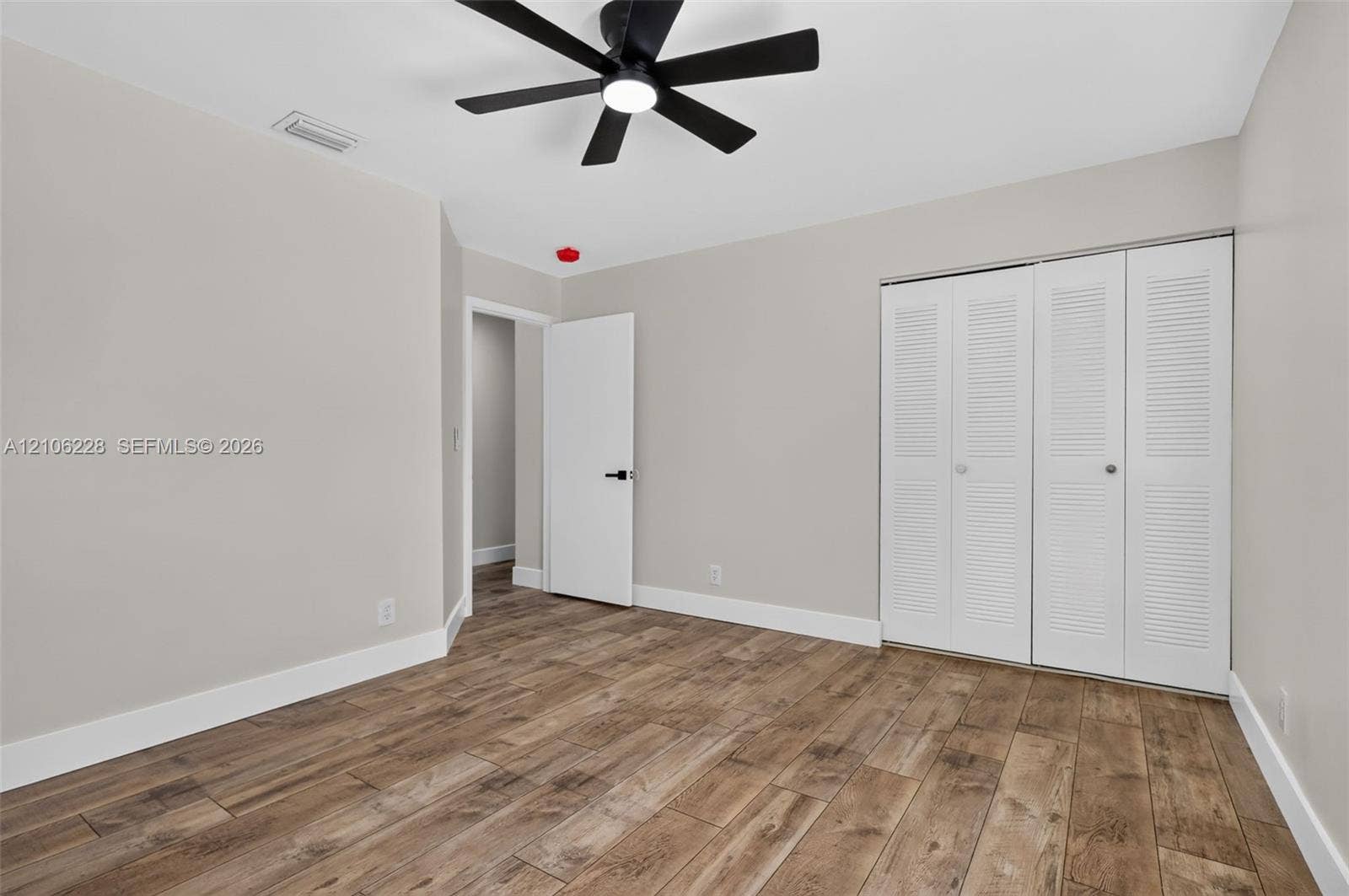 10760 SW 11th Drive, Davie, FL 33324 Wood-finish flooring, matte black ceiling fan with integrated lighting, and white louvered-door closet