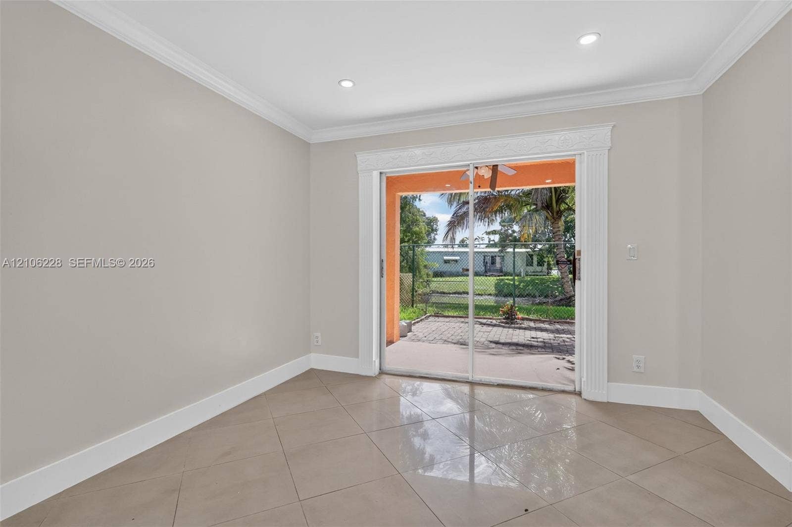 10760 SW 11th Drive, Davie, FL 33324 Neutral interior featuring large-format ceramic tile flooring, recessed ceiling lighting, crown molding, and sliding glass doors with decorative casing