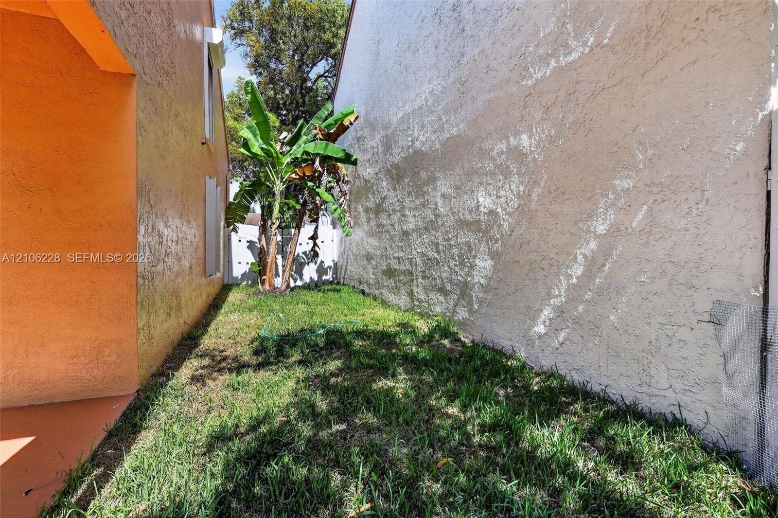 10760 SW 11th Drive, Davie, FL 33324 Side yard exterior featuring textured stucco walls, grass lawn, and landscaping