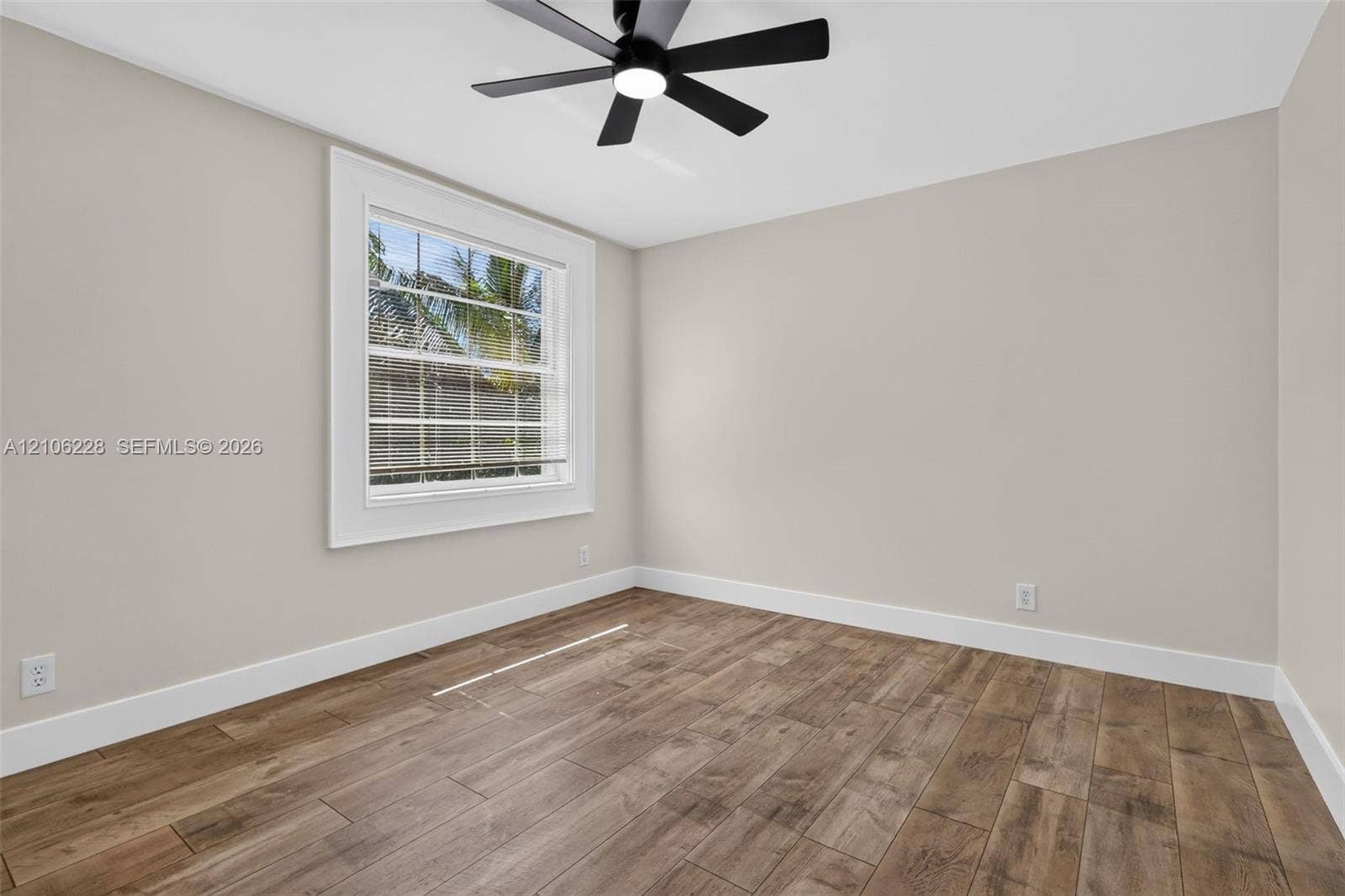 10760 SW 11th Drive, Davie, FL 33324 Wood-finish flooring, multi-pane window with white casing, and matte black ceiling fan with integrated lighting