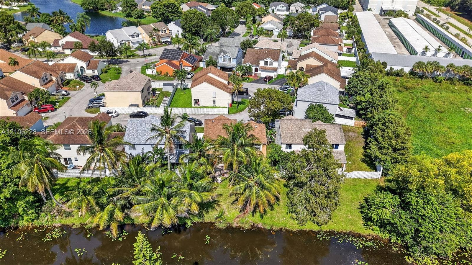 10760 SW 11th Drive, Davie, FL 33324 Aerial perspective of a suburban neighborhood featuring paved streets, multi-level residential structures, mature palm trees, and canal-front positioning
