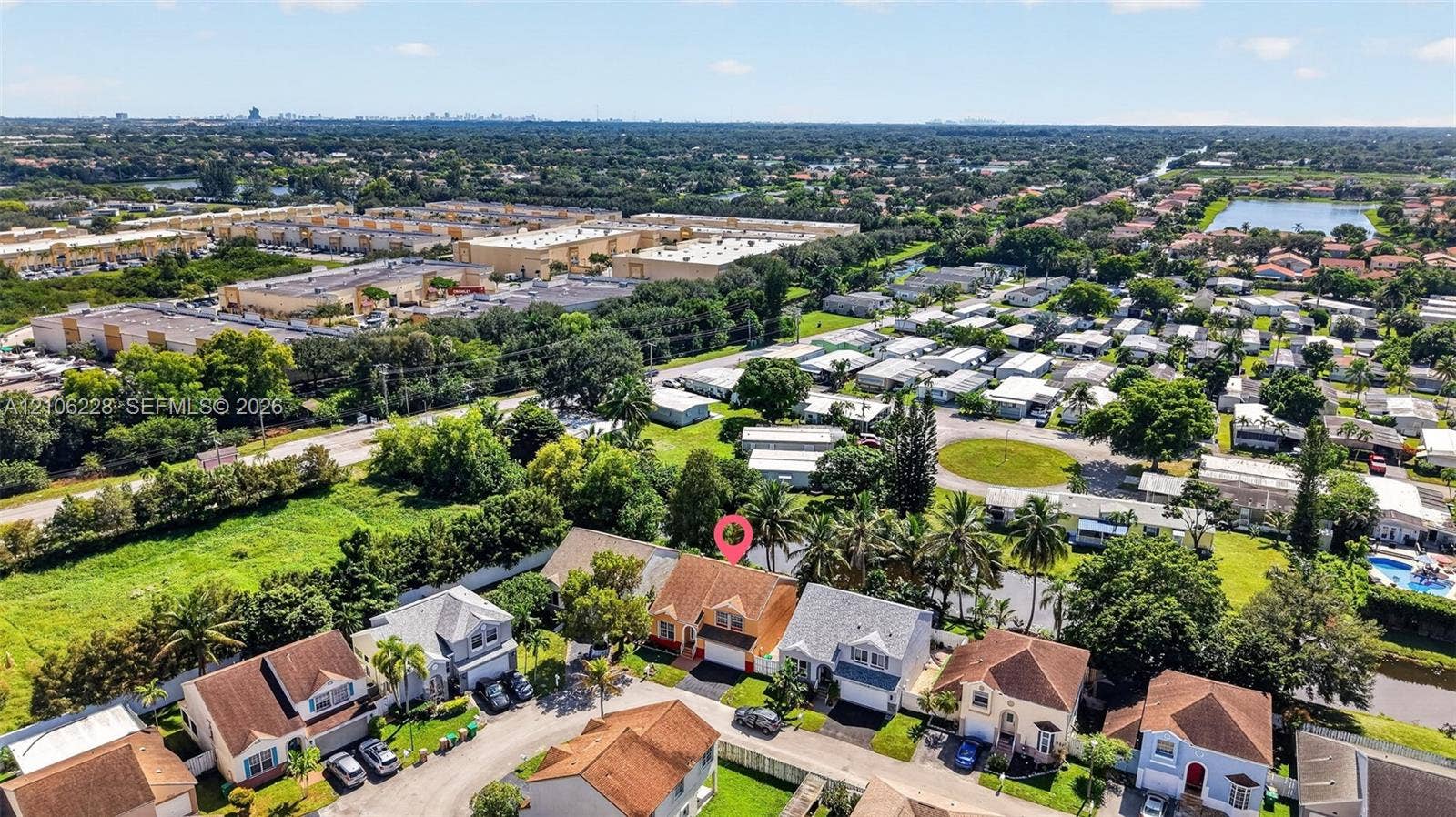10760 SW 11th Drive, Davie, FL 33324 Aerial perspective of a multi-story residence featuring a shingled roof, attached garage, and mature palm trees