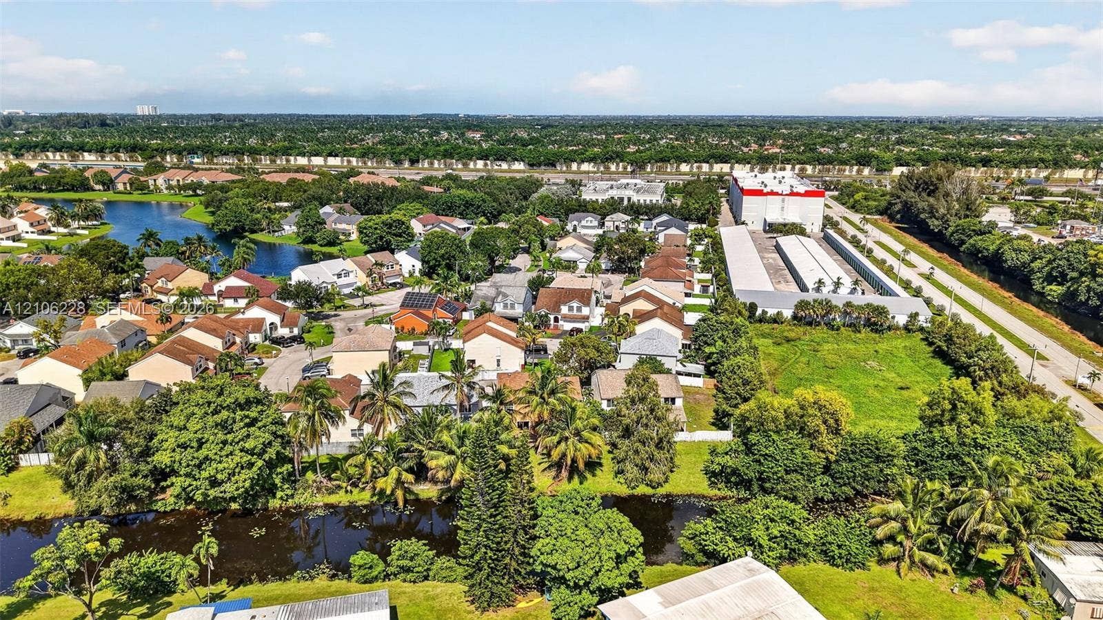 10760 SW 11th Drive, Davie, FL 33324 Aerial perspective of the residential area featuring a canal, mature trees, dense greenery, and proximity to regional infrastructure