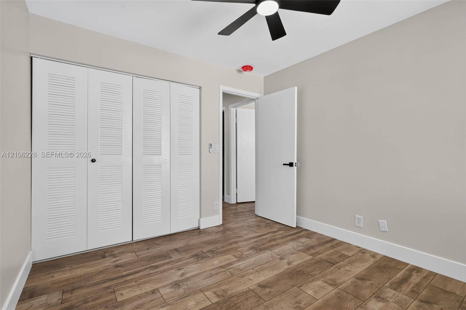 10760 SW 11th Drive, Davie, FL 33324 Wood-finish flooring, white louvered-door closet, and modern black ceiling fan with integrated lighting