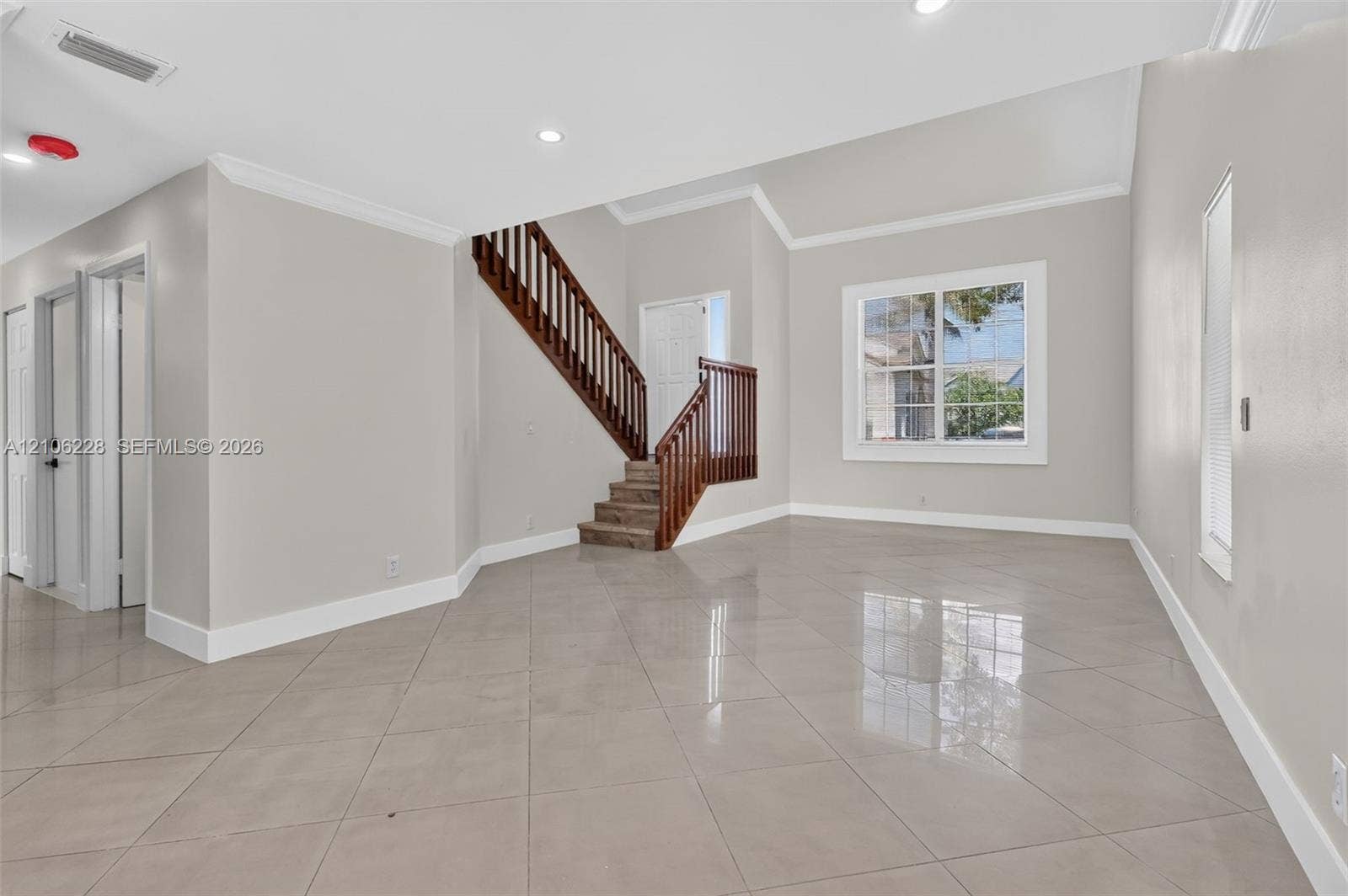 10760 SW 11th Drive, Davie, FL 33324 High-ceilinged room featuring large-format ceramic tile flooring, a staircase with a dark wood-finish balustrade, crown molding, and recessed lighting