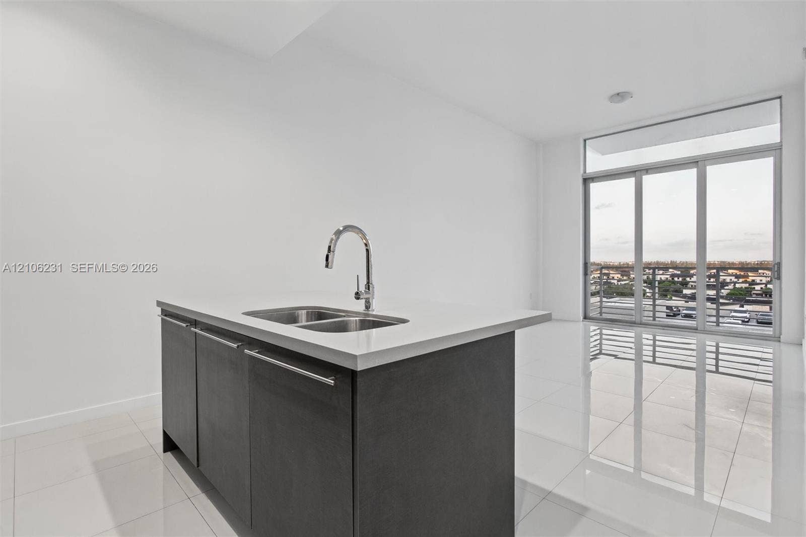 7875 NW 107th Avenue, #802, Doral, FL 33178 Center island featuring a stone countertop, dual-basin stainless steel sink, and high-arc chrome faucet, paired with dark cabinetry and polished tile flooring, highlighted by floor-to-ceiling glass sliding doors