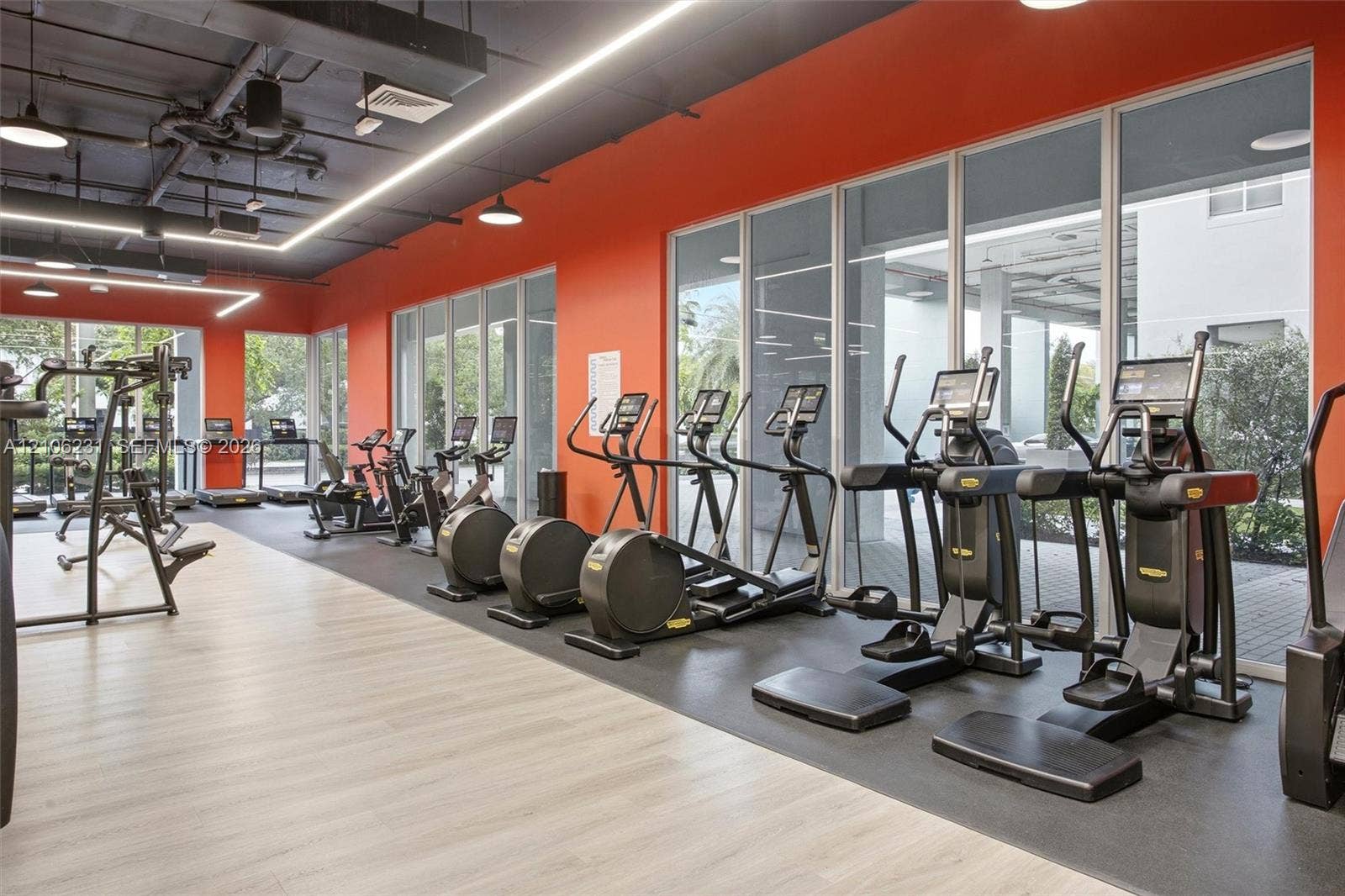 7875 NW 107th Avenue, #802, Doral, FL 33178 Fitness facility with modern exercise equipment, rubberized exercise surfacing, and an exposed industrial-style ceiling with recessed lighting
