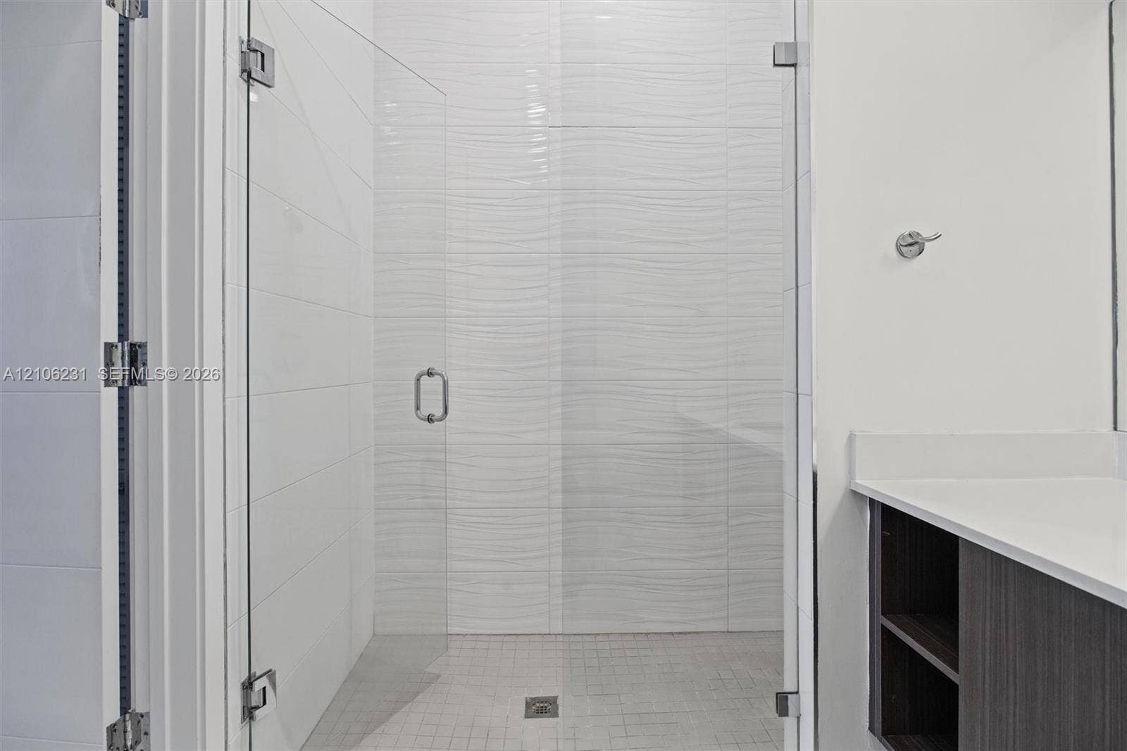 7875 NW 107th Avenue, #802, Doral, FL 33178 Walk-in shower featuring a frameless glass door, textured wave-pattern wall tile, mosaic floor tiling.