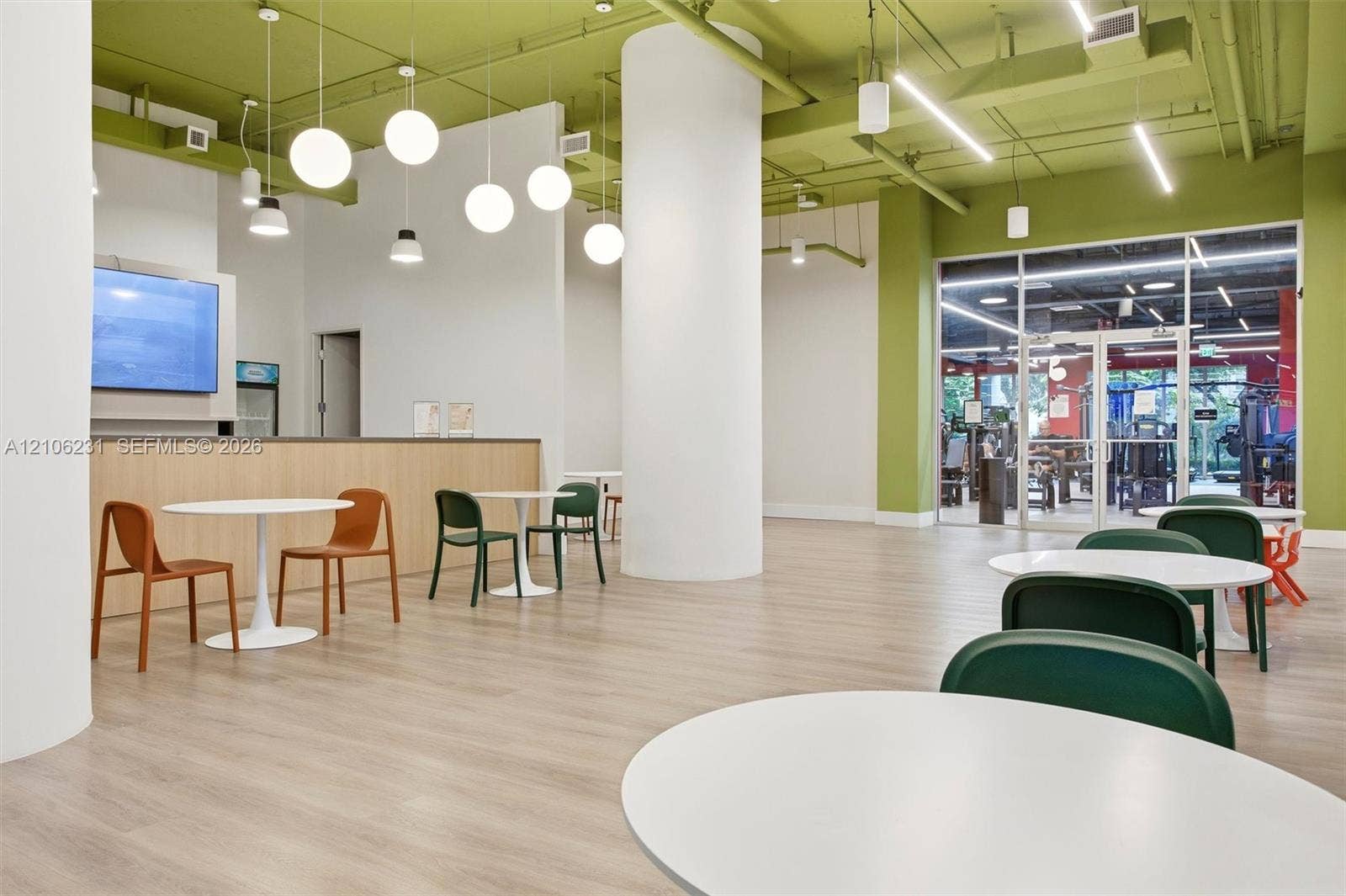 7875 NW 107th Avenue, #802, Doral, FL 33178 Open-concept space featuring wood-finish flooring, exposed industrial ceiling with pendant globe lighting, structural cylindrical columns, and full-height glass entry doors