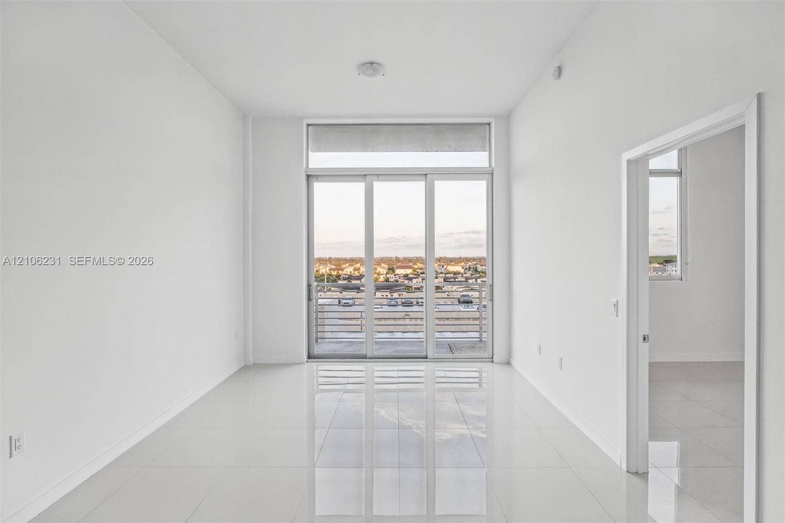 7875 NW 107th Avenue, #802, Doral, FL 33178 Interior space featuring 24x24 tile flooring, floor-to-ceiling glass sliding doors, and a private balcony with horizontal metal railings